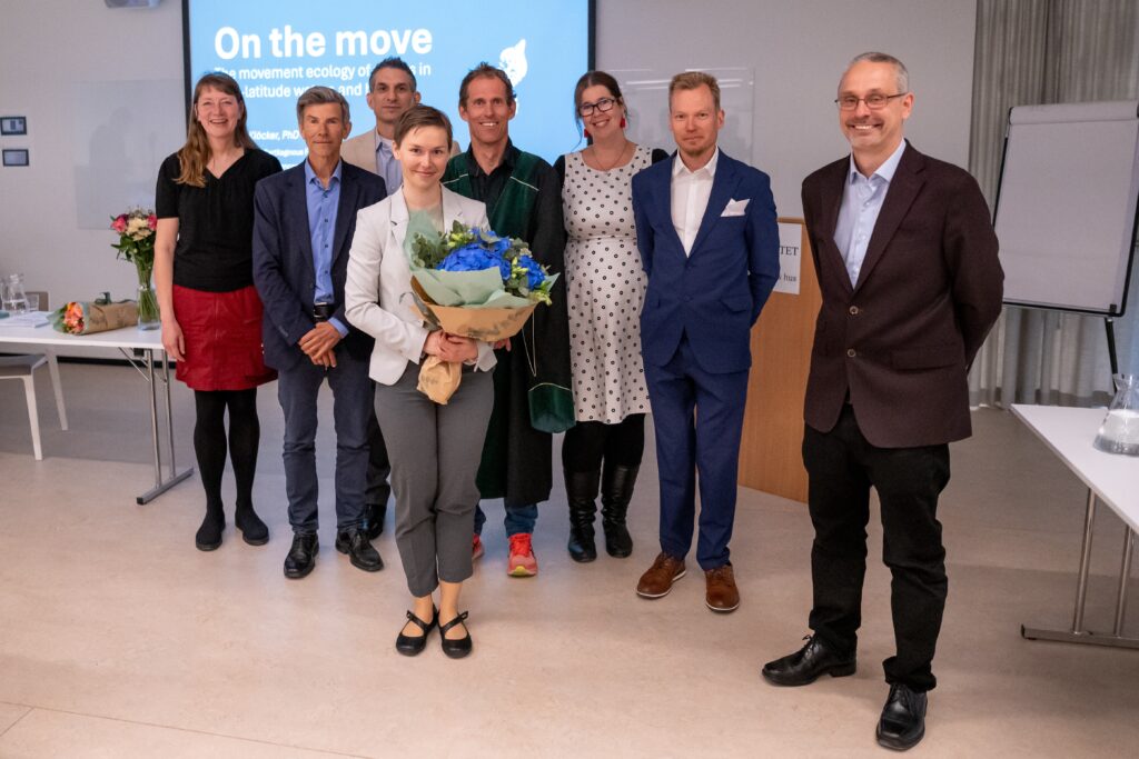 Eight people standing, Dr. Klöcker in the middle holding flowers.